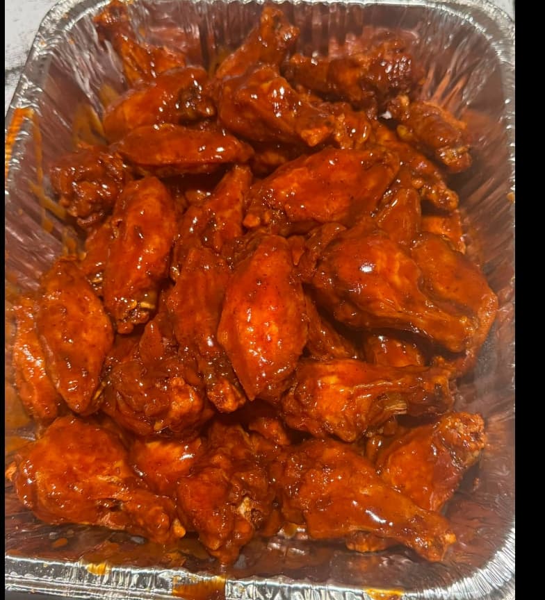 Pan of crispy wings tossed in buffalo sauce